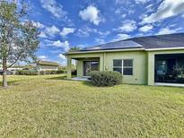 Green home featuring a screened-in patio, green lawn, and solar panels for energy efficiency at 1718 Trailwater St, Ruskin, FL 33570