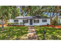 Charming home featuring a manicured lawn, fresh mulch, and inviting brick pathway at 4202 W Bay Vista Ave, Tampa, FL 33611