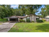 Charming single-story home featuring a stone accent wall, large lawn, and a convenient two-car carport at 4401 W Sam Allen Rd, Plant City, FL 33565