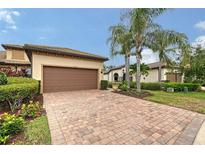 Charming home with a brick driveway, two-car garage, lush landscaping, and stately palm trees at 17109 Kenton Ter, Bradenton, FL 34202