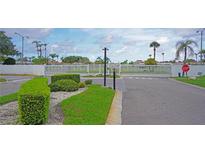Gated community entrance with white fencing, manicured landscaping, and a clearly marked stop sign at 4329 Tahitian Gardens Cir # B, Holiday, FL 34691