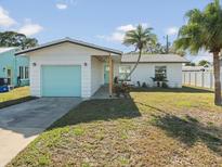 Charming home with a bright, colorful garage door, palm trees, and inviting curb appeal at 15810 2Nd E St, Redington Beach, FL 33708