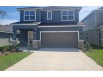 Two-story home with gray siding, brown garage door, and stone accents at 36104 Trinity Glade Rd, Dade City, FL 33525