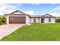 Single-story home with a two-car garage and landscaped lawn at 6007 Gillot Blvd, Port Charlotte, FL 33981