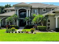 Elegant home featuring a tile roof, well-manicured lawn, and lush tropical landscaping with palm trees at 5016 Givendale Ln, Tampa, FL 33647