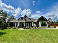 Charming single-story home featuring stone accents, a covered porch, and a lush green lawn at 17059 Nokota Ave, Hudson, FL 34667