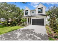 Stunning two-story home featuring a modern design, lush landscaping, and a gray brick driveway at 3109 W Knights Ave, Tampa, FL 33611