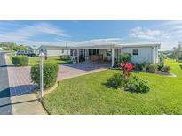Single-wide mobile home with carport, landscaped yard, and paved driveway at 37532 New Horizons Blvd, Zephyrhills, FL 33541