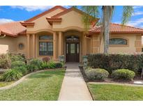 Tan two-story house with terracotta roof and lush landscaping at 12748 Grand Traverse Dr, Dade City, FL 33525