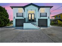 Charming two-story home featuring a unique aqua and white color scheme, double garages, and elevated entry with black railings at 3230 Azalea Drive # Lot 13, Hernando Beach, FL 34607