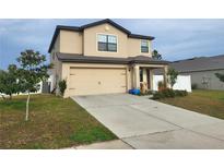 Two story house with beige siding and a two car garage at 6949 Crested Orchid Dr, Brooksville, FL 34602