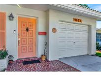 Ranch-style home with a peach door, attached garage, and well-manicured lawn at 9622 41St N Way, Pinellas Park, FL 33782