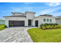 Modern two-story house with a white exterior, gray roof, and a paver driveway at 32298 Wetland Bird Vw, San Antonio, FL 33576