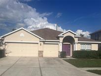 Two-story house with a three-car garage and a purple front door at 4320 Edenrock Pl, Spring Hill, FL 34609