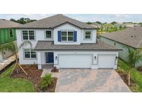 Two-story home with blue shutters and a brick paver driveway at 4939 Eagle Rock Dr, Wimauma, FL 33598