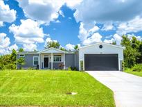 Gray house with white trim, two-car garage, and green lawn at 338 Stevensville St, Port Charlotte, FL 33954