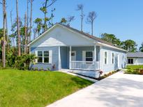 Charming one-story home with light blue siding, a white porch, and a landscaped yard at 18078 Spartonvail Ave, Port Charlotte, FL 33954