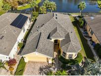 A yellow single-story home with an attached garage, a gray roof, and is located on a pond at 1007 Emerald Dunes Dr, Sun City Center, FL 33573