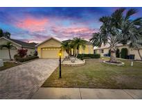 Charming single-story home with a well-manicured lawn and a brick driveway leading to a two-car garage at 1007 Emerald Dunes Dr, Sun City Center, FL 33573
