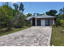 House exterior with a brick driveway and two car garage at 22491 Delhi Ave, Port Charlotte, FL 33952