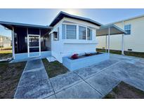 Charming home with light blue trim, enclosed porch, flower box, and covered parking at 116 W Saint Johns Way, Apollo Beach, FL 33572