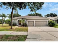 Charming single-story home features a three-car garage, manicured lawn, and mature landscaping at 12902 Cattail Shore Ln, Riverview, FL 33579