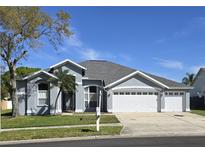 Charming single-story home featuring a three-car garage, manicured lawn, and beautiful landscaping at 28330 Openfield Loop, Wesley Chapel, FL 33543