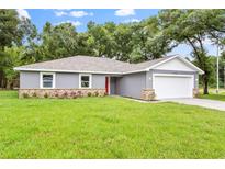 Charming single-story home with gray exterior, stone accents, and a well-manicured lawn at 11734 Orange Ct, Dade City, FL 33525