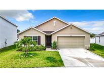 Tan one-story house with two-car garage and landscaping at 13292 Golden Lime Ave, Spring Hill, FL 34609
