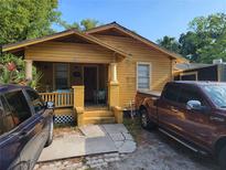 Yellow house with front porch, steps, and two parked vehicles at 2607 E 26Th Ave, Tampa, FL 33605
