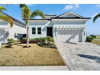 Charming light blue home featuring a well-manicured lawn, paved driveway, and attached two-car garage at 6542 Simone Shores Cir, Apollo Beach, FL 33572