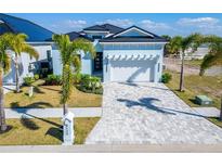 Charming, light-blue single-Gathering home featuring a well-manicured lawn, paver driveway, and a two-car garage at 6542 Simone Shores Cir, Apollo Beach, FL 33572