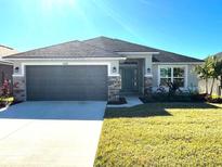 One-story home with gray siding, stone accents, and a two-car garage at 36188 Welsh Glade Rd, Dade City, FL 33525