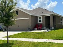 Charming one-story home with two-car garage and red chairs at 16743 Trite Bend St, Wimauma, FL 33598