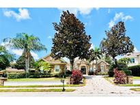 Charming home showcasing lush landscaping, palm trees, and a brick paved driveway at 1227 Toscano Dr, Trinity, FL 34655