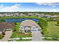 Beautiful two-story home boasts a serene lake view, lush landscaping and paver driveway at 7135 Graybrook Dr, Wesley Chapel, FL 33545