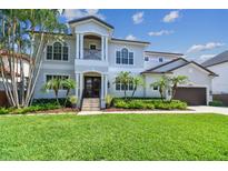 Beautiful two-story home featuring a manicured lawn and lush tropical landscaping with palm trees enhancing the curb appeal at 5013 W Leona St, Tampa, FL 33629