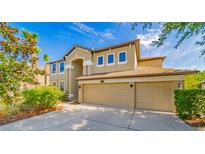 Two-story house with beige exterior, two-car garage, and landscaping at 11820 Gilmerton Dr, Riverview, FL 33579