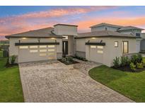Modern two-story home featuring a three-car garage, and a brick driveway at 8320 Golden Beach Ct, Parrish, FL 34219
