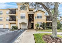 Exterior of a tan building with garages, balconies, and manicured landscaping at 5125 Palm Springs Blvd # 1303, Tampa, FL 33647