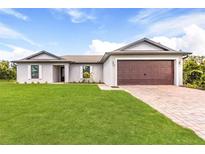 Single-story home with a two-car garage and a lush green lawn at 12564 Feldman Ave, Port Charlotte, FL 33981