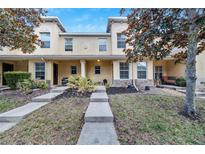 Exterior view of a tan townhome with a stone accent, front porch and landscaping at 10957 Keys Gate Dr, Riverview, FL 33579