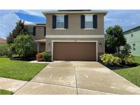 Two-story house with brown garage door and landscaping at 228 Star Shell Dr, Apollo Beach, FL 33572