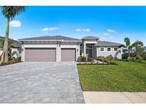 Beautifully landscaped, single-story home with a three-car garage and paver driveway under a bright, sunny sky at 10385 Sunday Dr, Port Charlotte, FL 33981