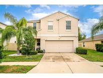 Two story house with beige exterior, two car garage, and palm trees at 409 Serenity Mill Loop, Ruskin, FL 33570