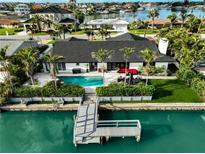 Beautiful waterfront home featuring a private dock and an inviting pool surrounded by lush landscaping at 221 Howard Dr, Belleair Beach, FL 33786
