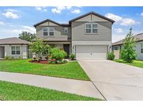 Charming two-story home with a well-manicured lawn and attached two-car garage at 6248 Bradford Woods Dr, Zephyrhills, FL 33542