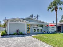 Charming single-story home features a yellow door, grey brick, manicured lawn, and a mature palm tree at 120 Chesapeake Ave, Tampa, FL 33606