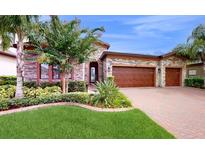 Two-story house with stone facade and three-car garage at 11411 Drifting Leaf Dr, Riverview, FL 33579