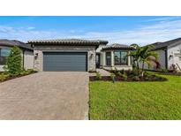 Single-story home with gray garage door, paver driveway, and landscaped yard at 1871 Pepper Grass Dr, North Port, FL 34289